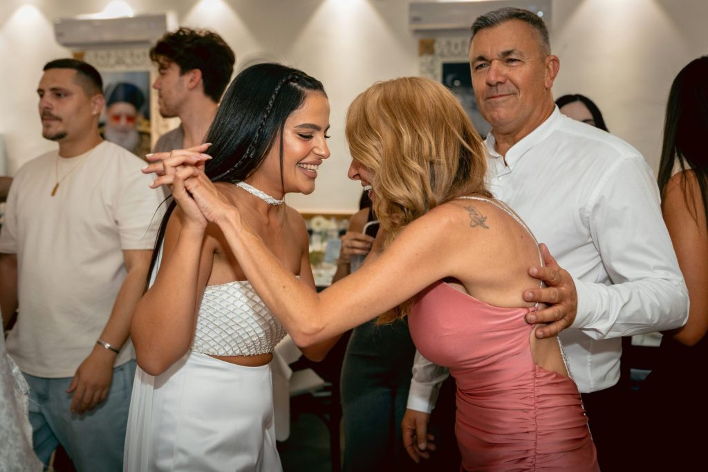 Two smiling women dancing at a lively indoor party